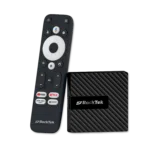 RockTek GB1 Android TV box shown alongside its dedicated remote control. The compact device has a sleek, textured design. The remote features a circular navigation pad, voice control button, and dedicated buttons for popular streaming services like YouTube, Netflix, and Prime Video, along with an 'Apps' button for quick access to installed applications