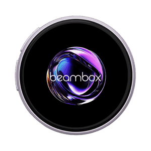 A circular badge or display, framed by a light purple/lavender-colored metal ring. The black display area shows a highly reflective, swirling purple and NIKKO-BADGE-TS-SLIVER-IMAGE-1.png: A circular badge or display, framed by a silver metal ring. The black display area shows a highly reflective, swirling purple and blue abstract orb, with the white text "beambox" overlaid near the bottom. The image is set against a dark green background.abstract orb, with the white text "beambox" overlaid near the bottom. The image is set against a dark green background.