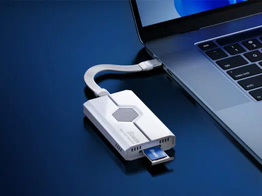 Close-up of the Biwin Mini SSD Reader connected to a laptop via a short USB-C cable, demonstrating a small form-factor Biwin SSD card being inserted into the reader's slot.