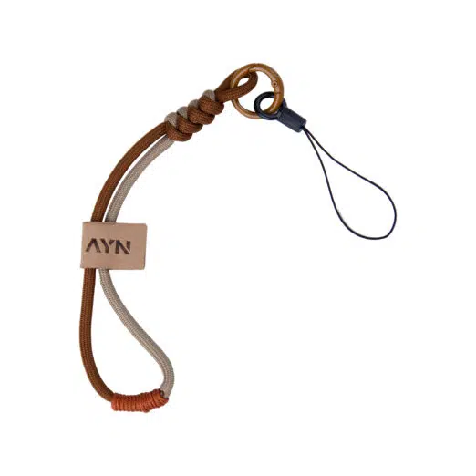 A durable paracord wrist lanyard featuring a dual-tone brown and tan braided design. It includes a small tan leather tag embossed with the "AYN" logo, a decorative snake knot at the top, and a bronze-colored carabiner attached to a thin black loop for securing handheld devices.
