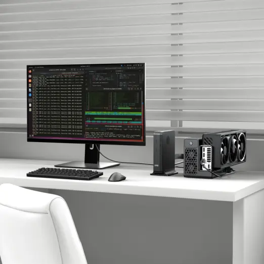 Front angled view of matte black GPD BOX GPD Mini PC with PCIe eGPU, triple-fan GPU and code monitor on white desk
